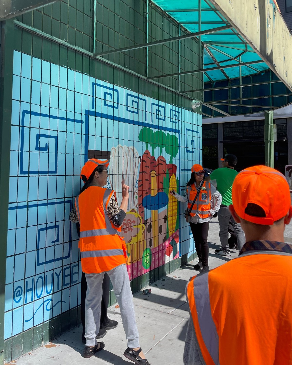 Volunteers in front of a mural by Houyee Chow